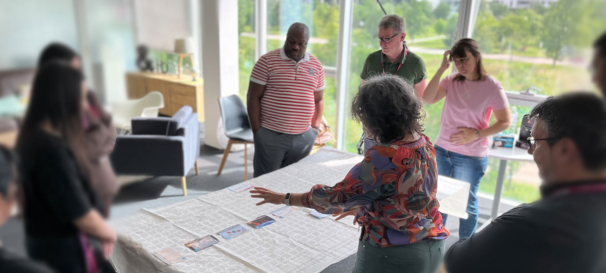 Un groupe échange autour d’une table avec des cartes, dans un bureau lumineux et convivial.