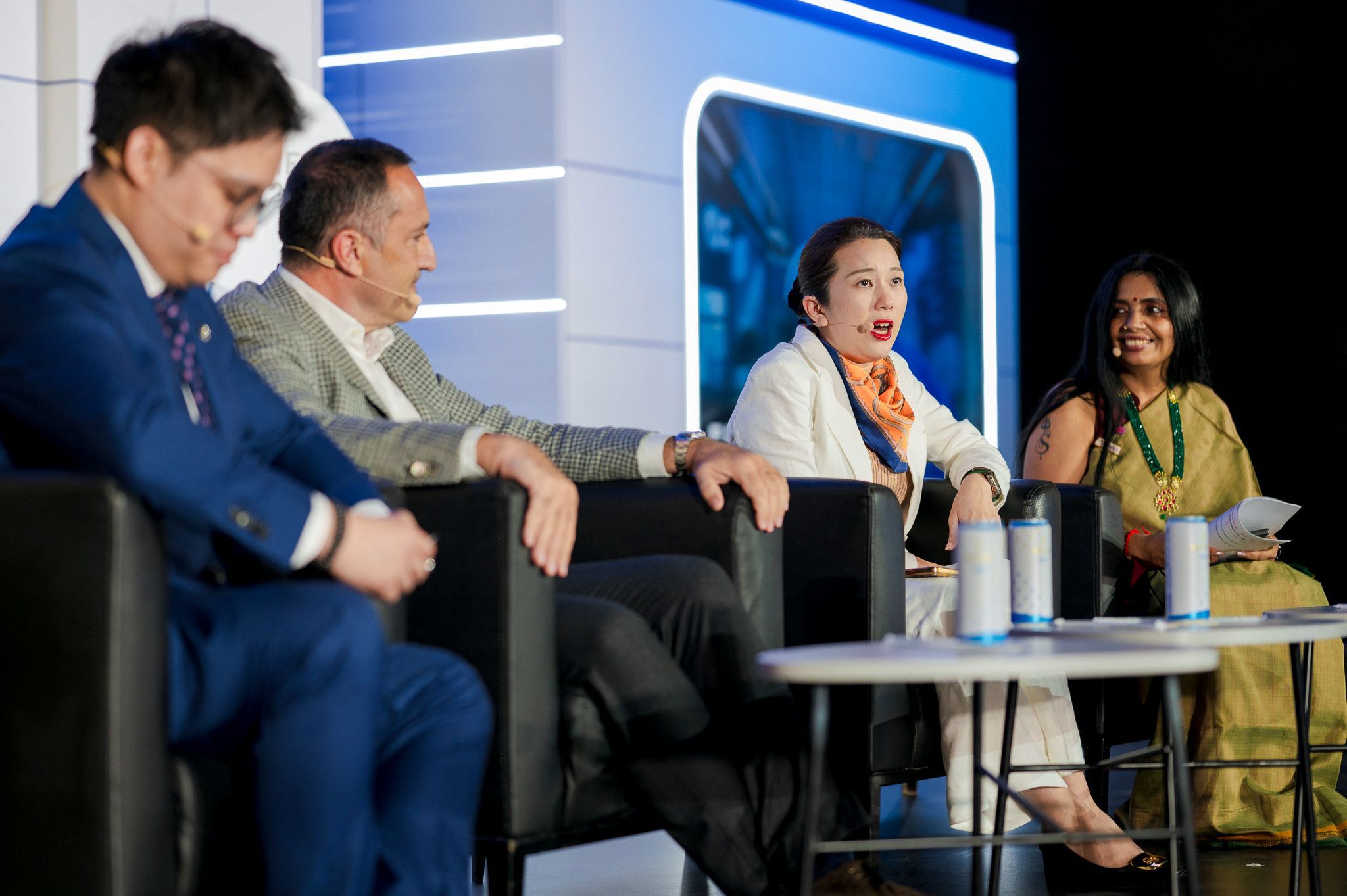 Four East Asian professionals laugh and collaborate in a bright modern office meeting