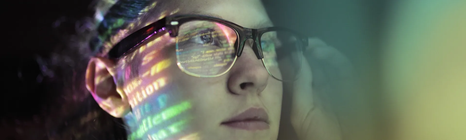 Close up of a young professional with code reflected in her glasses.