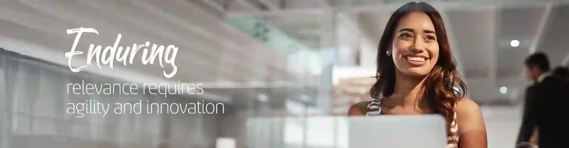 Smiling woman working on her laptop on a modern glass wall office
