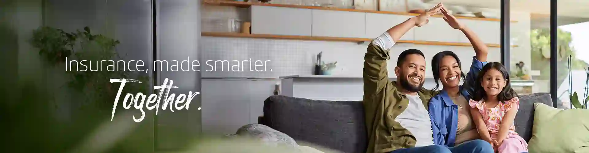 Smiling family sitting on a sofa at home, with parents forming a house gesture, representing TP’s Insurance page.