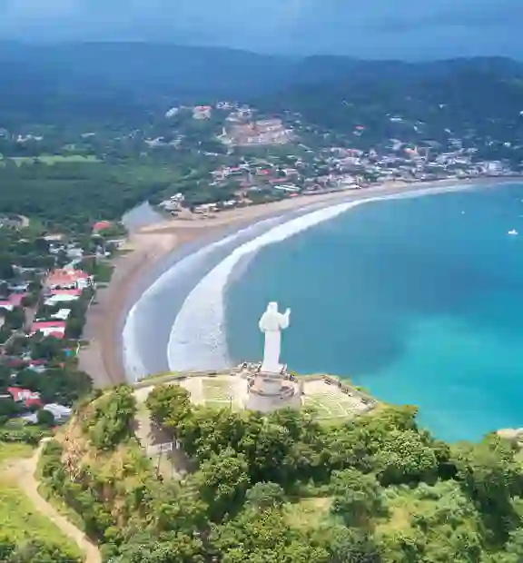 TP in Nicaragua - city view showing a statue in the foreground and a coastal city with crystal clear waters in the background