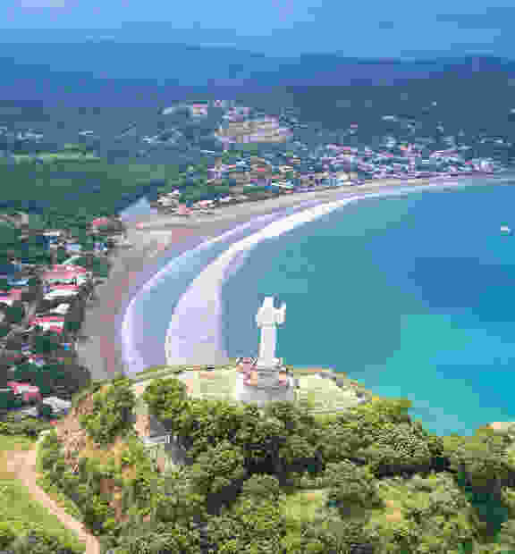 TP in Nicaragua - city view showing a statue in the foreground and a coastal city with crystal clear waters in the background