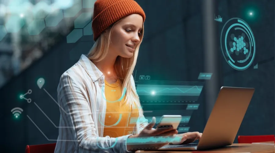 Woman using a laptop and a smartphone with data interface overlays.