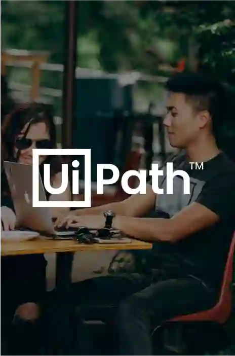 UiPath logo in focus and a couple using their laptops in the background