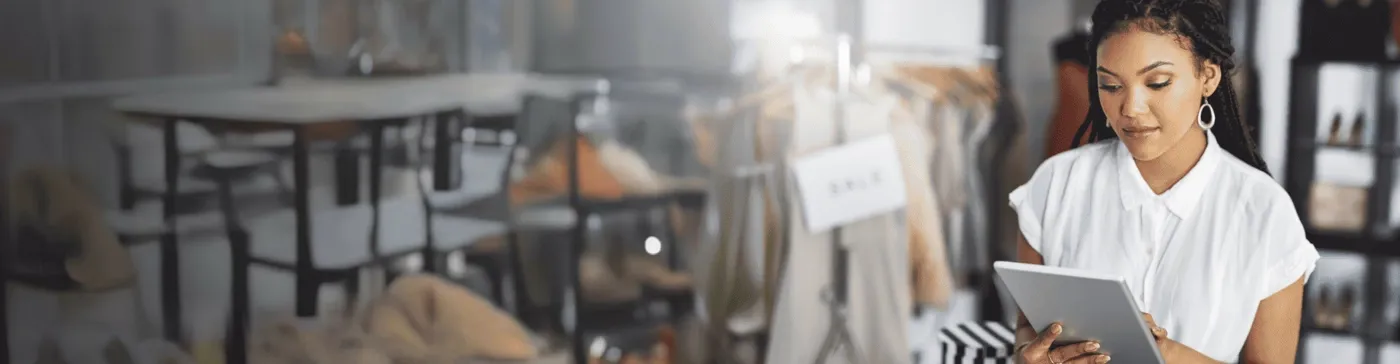 African saleswoman working on a tablet in a clothing store, illustrating TP’s Retail and E-commerce solutions.