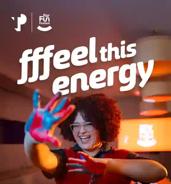 TP For Fun Festival banner with the phrase “Ffeel this energy” and a smiling person with painted hands.