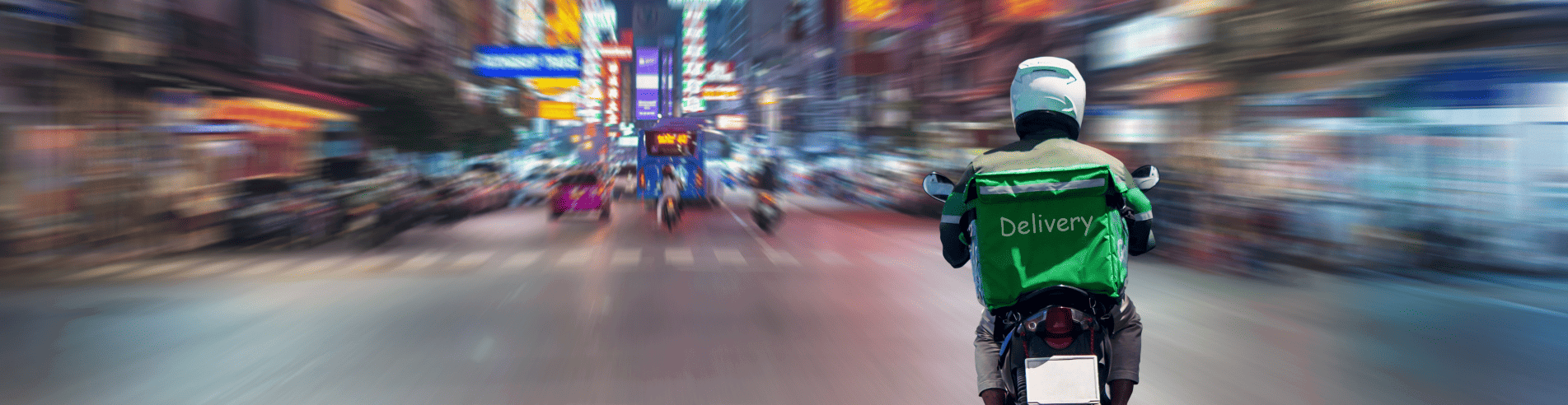 Delivery motorcycle in focus on a busy street at night