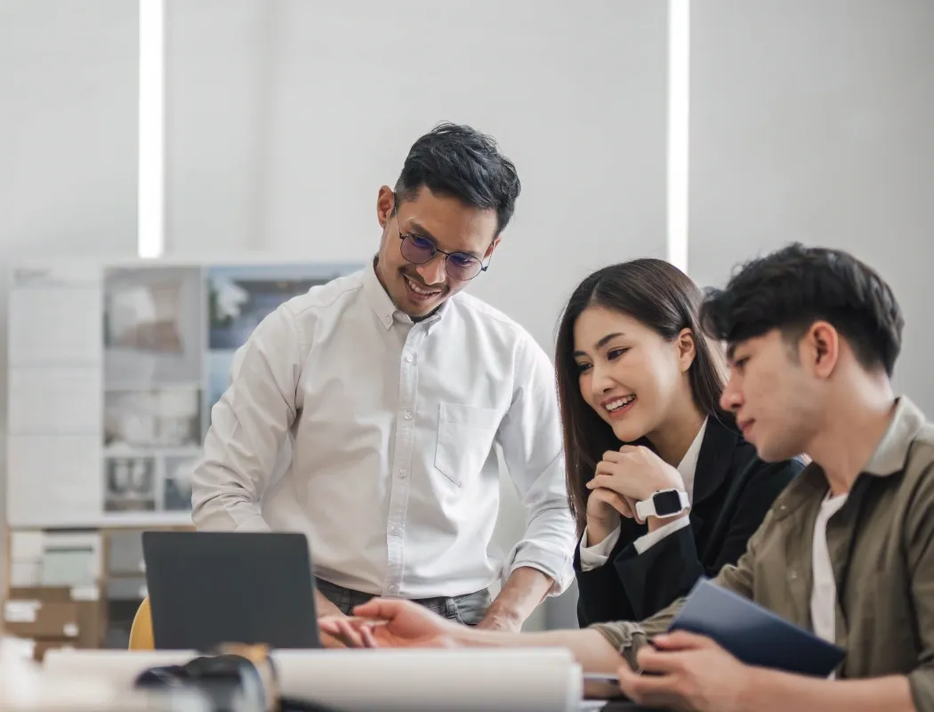 Three colleagues collaborate on a project in a bright office.