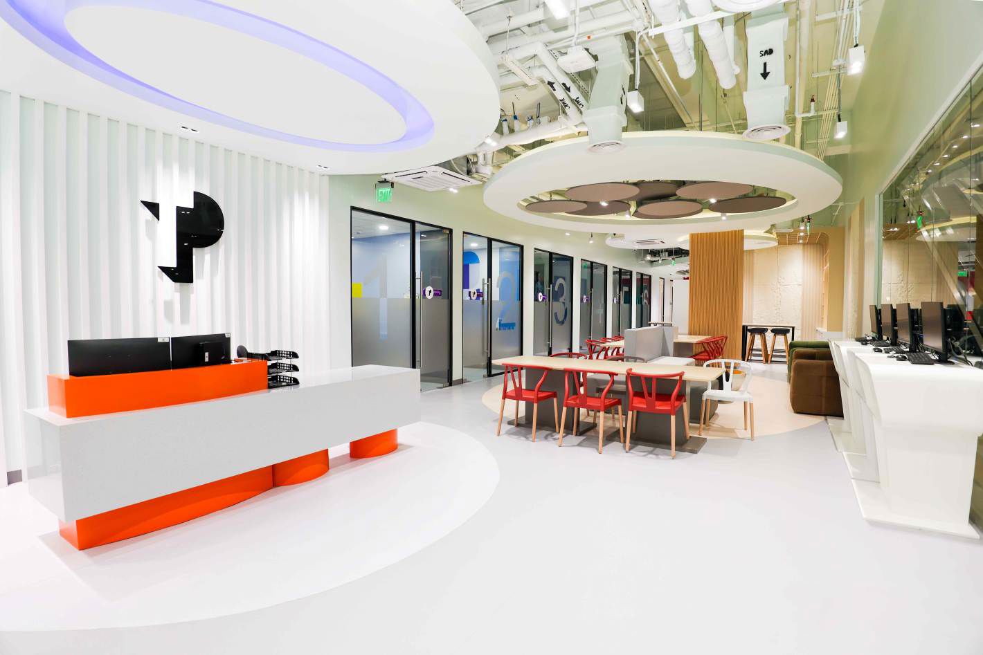 Modern TP office lobby with reception desk, meeting tables, and glass rooms.