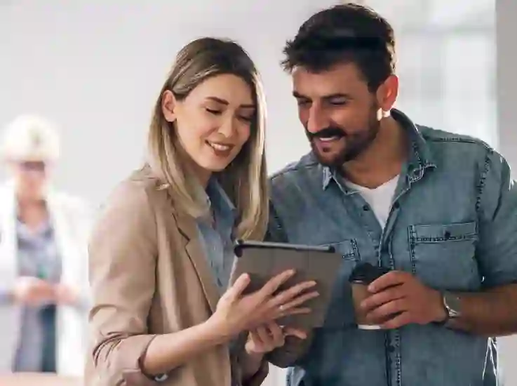 Smiling couple looking at a tablet, illustrating a case study on finance outsourcing driving $3.5M in annual savings.