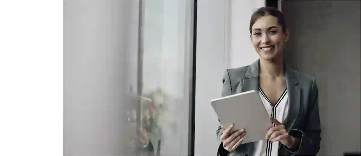 Smiling business woman working on her tablet in front of a bright office window