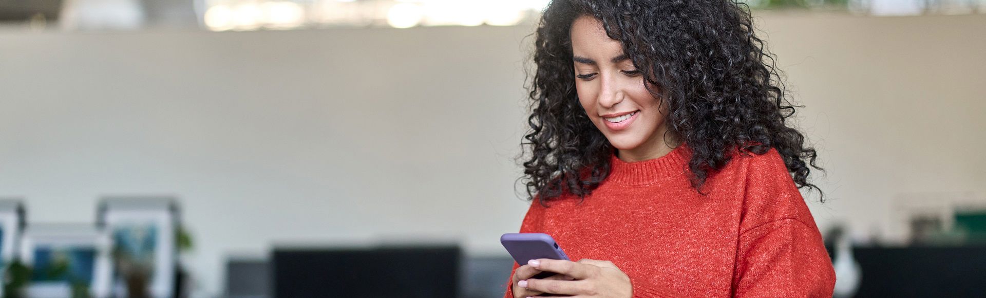 Young woman holding a smartphone, illustrating a blog about Anna AI, TP’s recruitment solution that blends AI, human expertise, and automation.