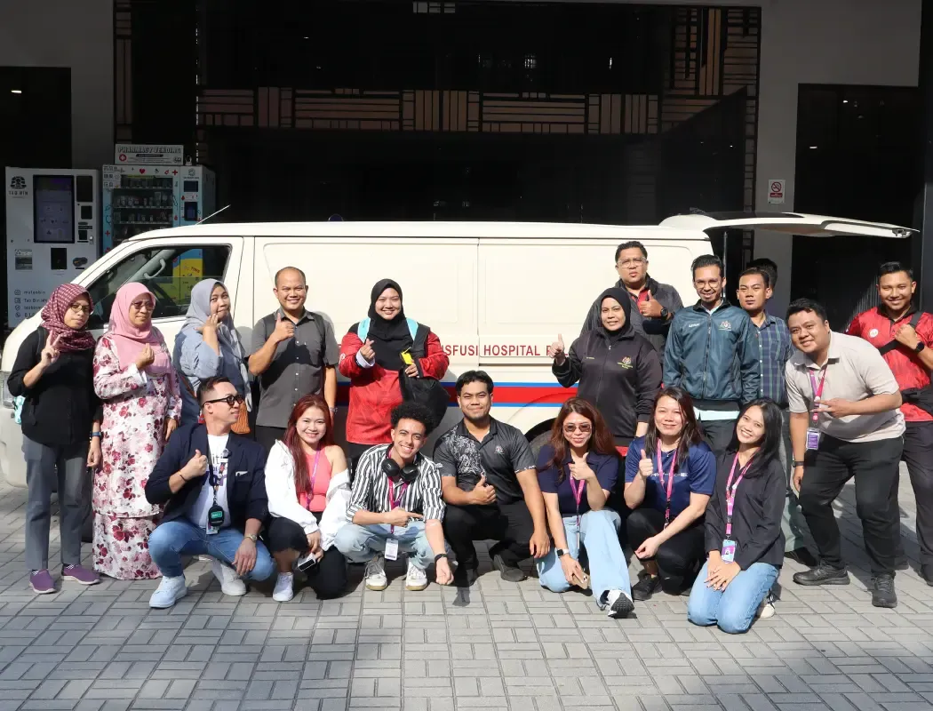 TP team members posing together during a community visit beside a hospital ambulance.