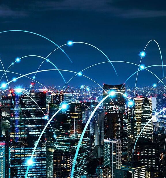City skyscrapers at night with glowing arcs symbolizing digital connectivity.