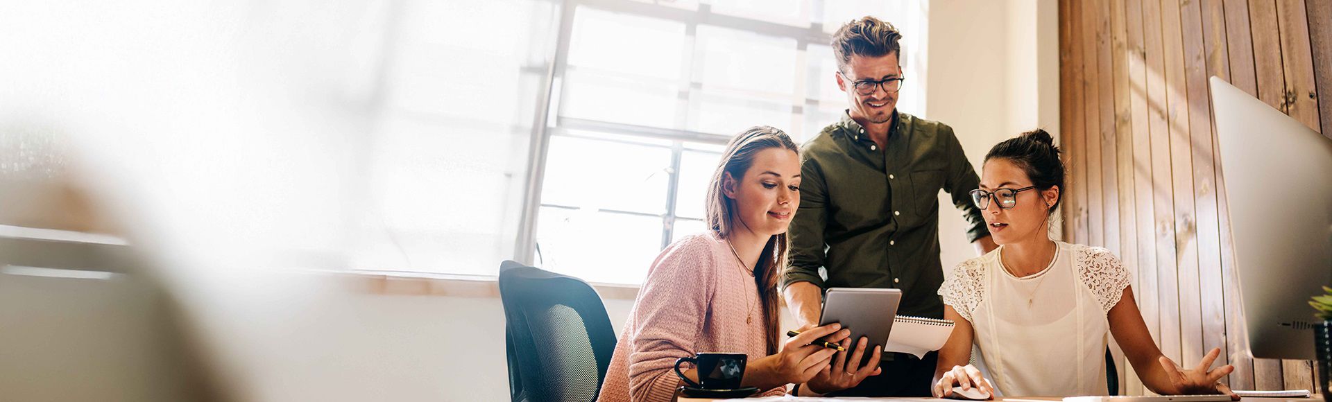Colleagues collaborating on a tablet in an office, representing TP’s blog on new hires becoming healthcare insurance experts.