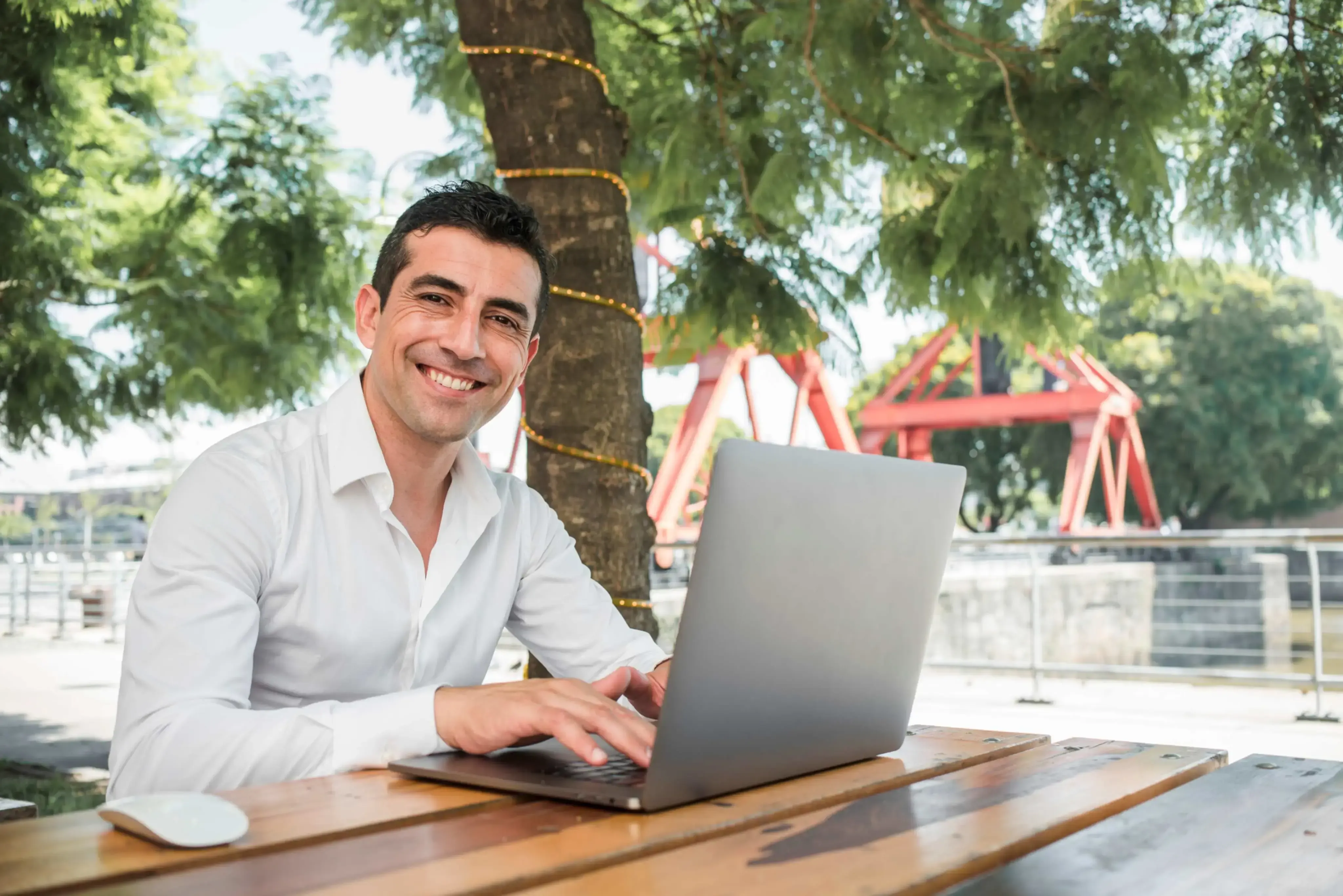 Man outdoor with a laptop in a wood table.