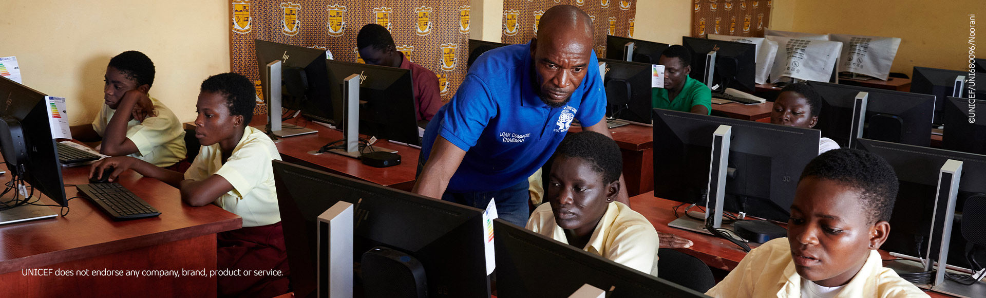 Teacher guiding girls using a computer in a technology learning environment.