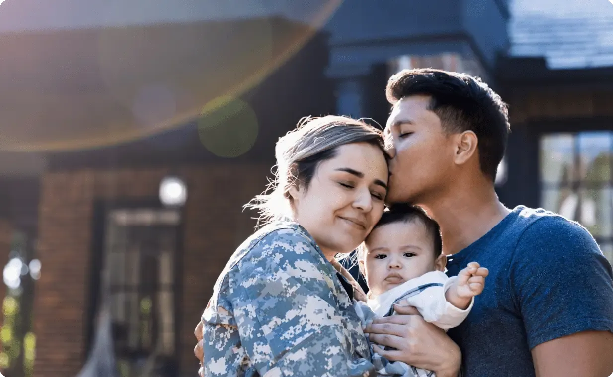 Man holding daughter and kissing his wife