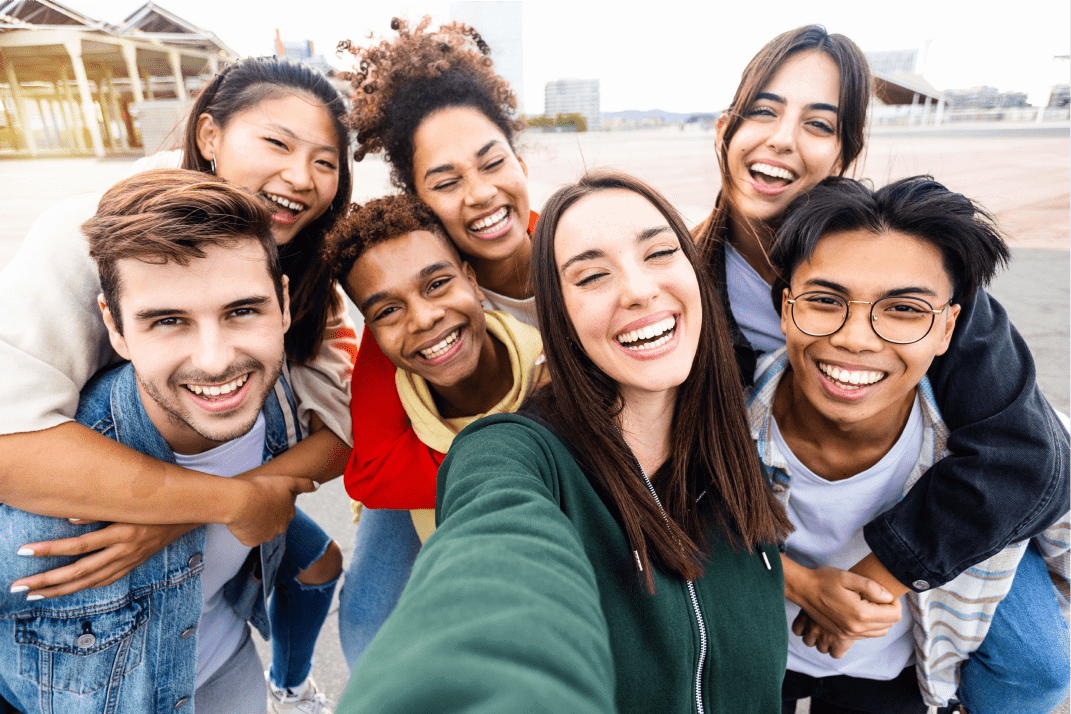 Group of diverse TP colleagues smiling and taking a selfie outdoors.
