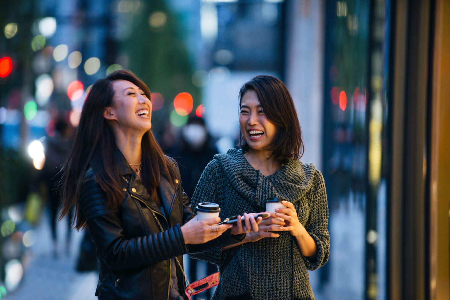 Smiling Asian friends having a cup of coffee on the streets 