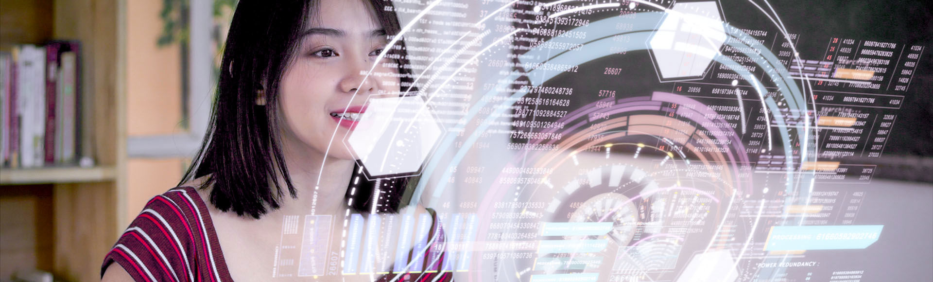 A young woman views futuristic glowing digital data dashboards in the office.