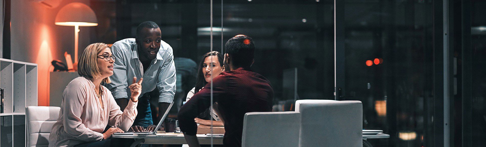 Group of four diverse professionals having a late-night meeting in a modern office. Group of four diverse professionals having a late-night meeting in a modern office.