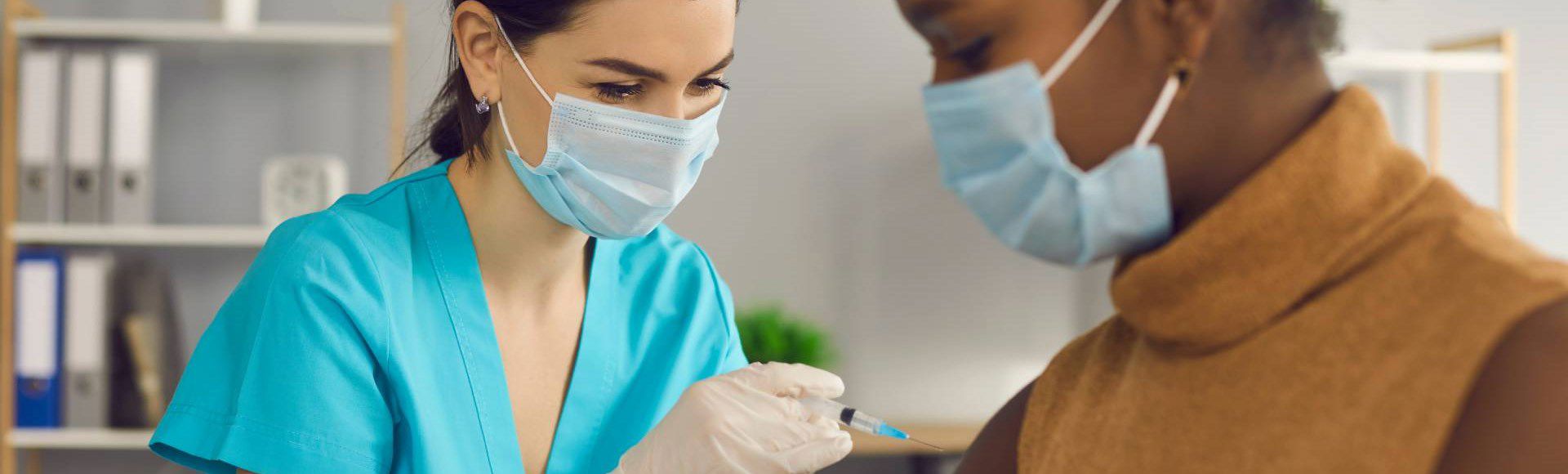 Healthcare professional administering a COVID-19 vaccine to a patient.