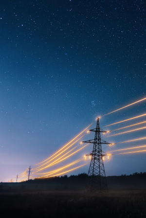 Линии электропередачи и башни ночью со светящимися световыми следами на фоне звёздного неба.