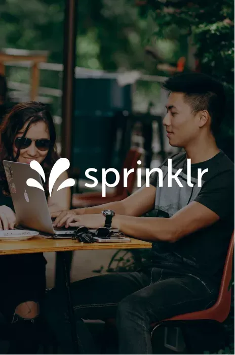 Sprinklr logo in focus with a couple working on the computer on the background