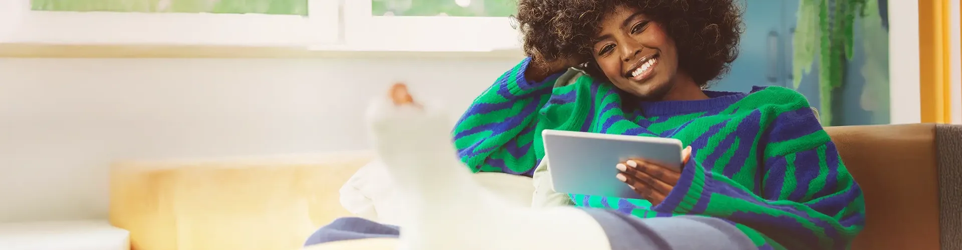Afro descendant woman with a leg cast using a tablet, reflecting trusted digital healthcare support.