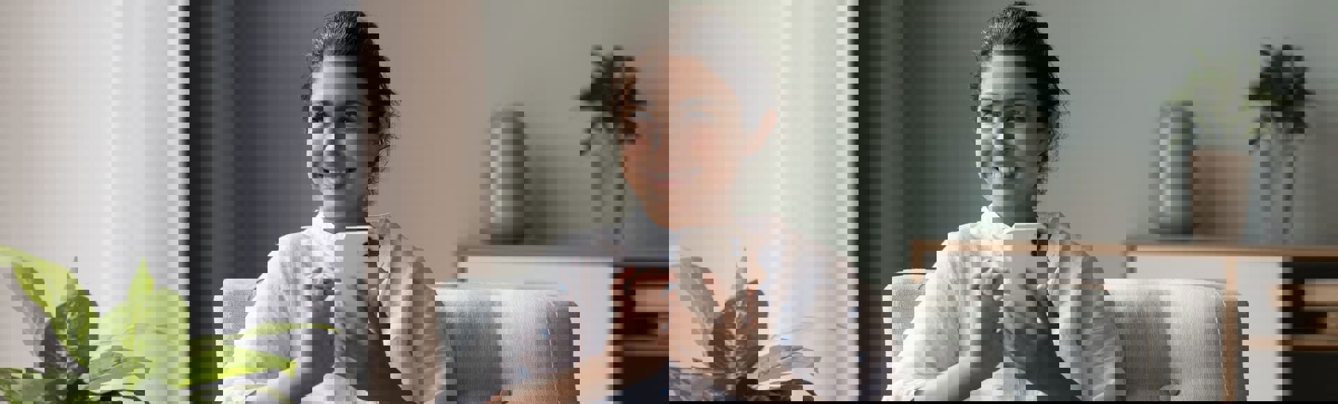 Woman sitting comfortably on her sofa, using her smartphone. The image illustrates a blog about empathy-driven and optimized debt recovery.