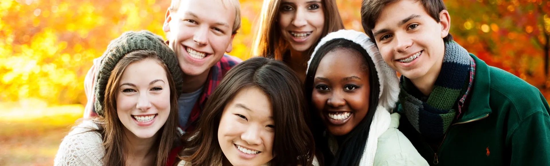 Smiling group of diverse young people posing together outdoors in autumn.