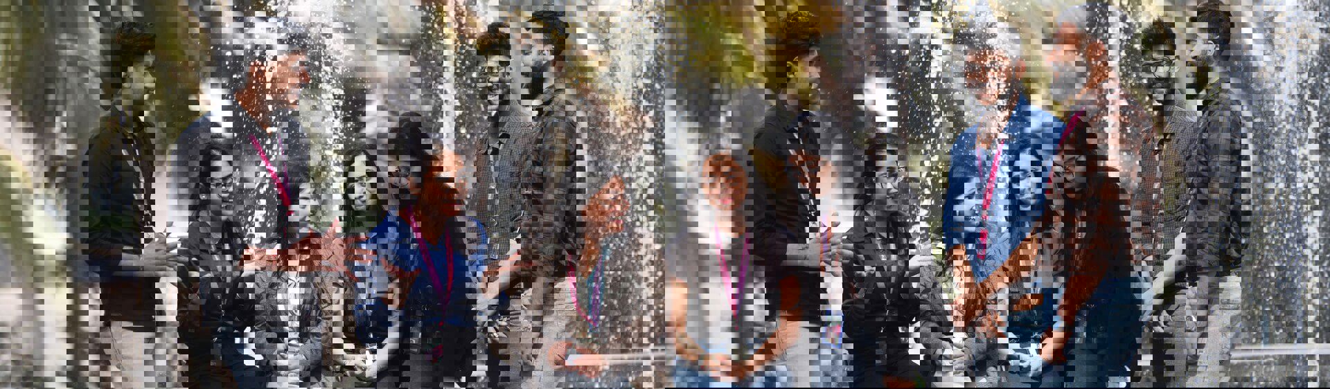 Group of TP employees talking and smiling near a fountain outdoors