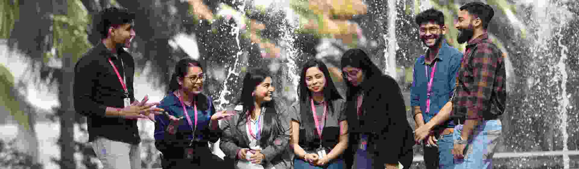 Group of TP employees talking and smiling near a fountain outdoors
