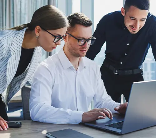 Business team collaborating on a laptop, illustrating TP’s insights on five key industry trends in ANZ claims services.