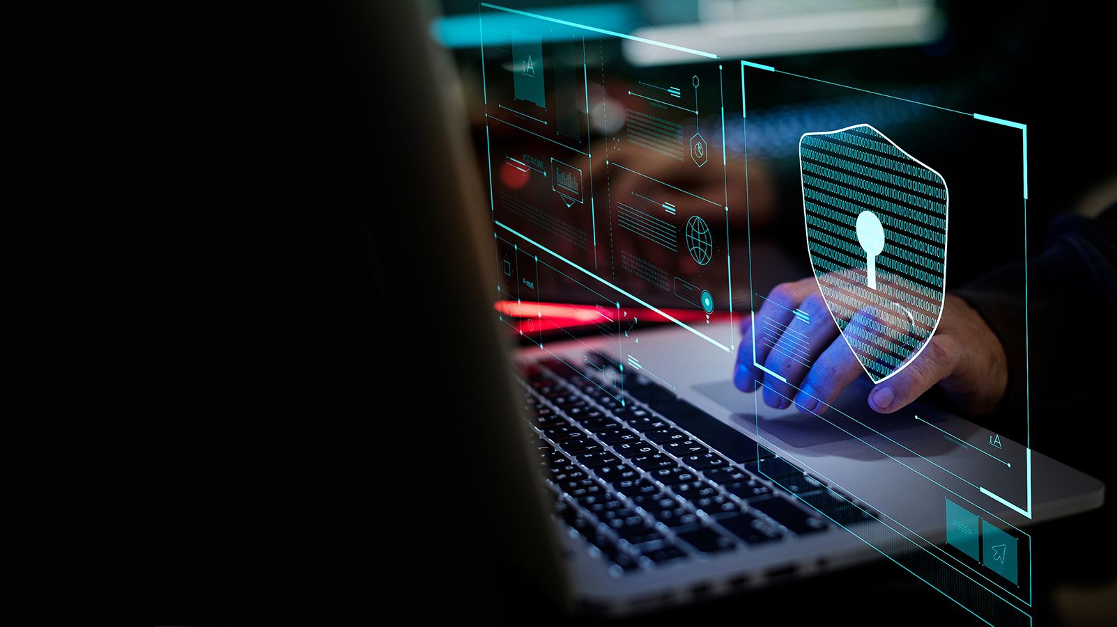Close-up of person using laptop with digital cybersecurity interface and shield icon representing data protection