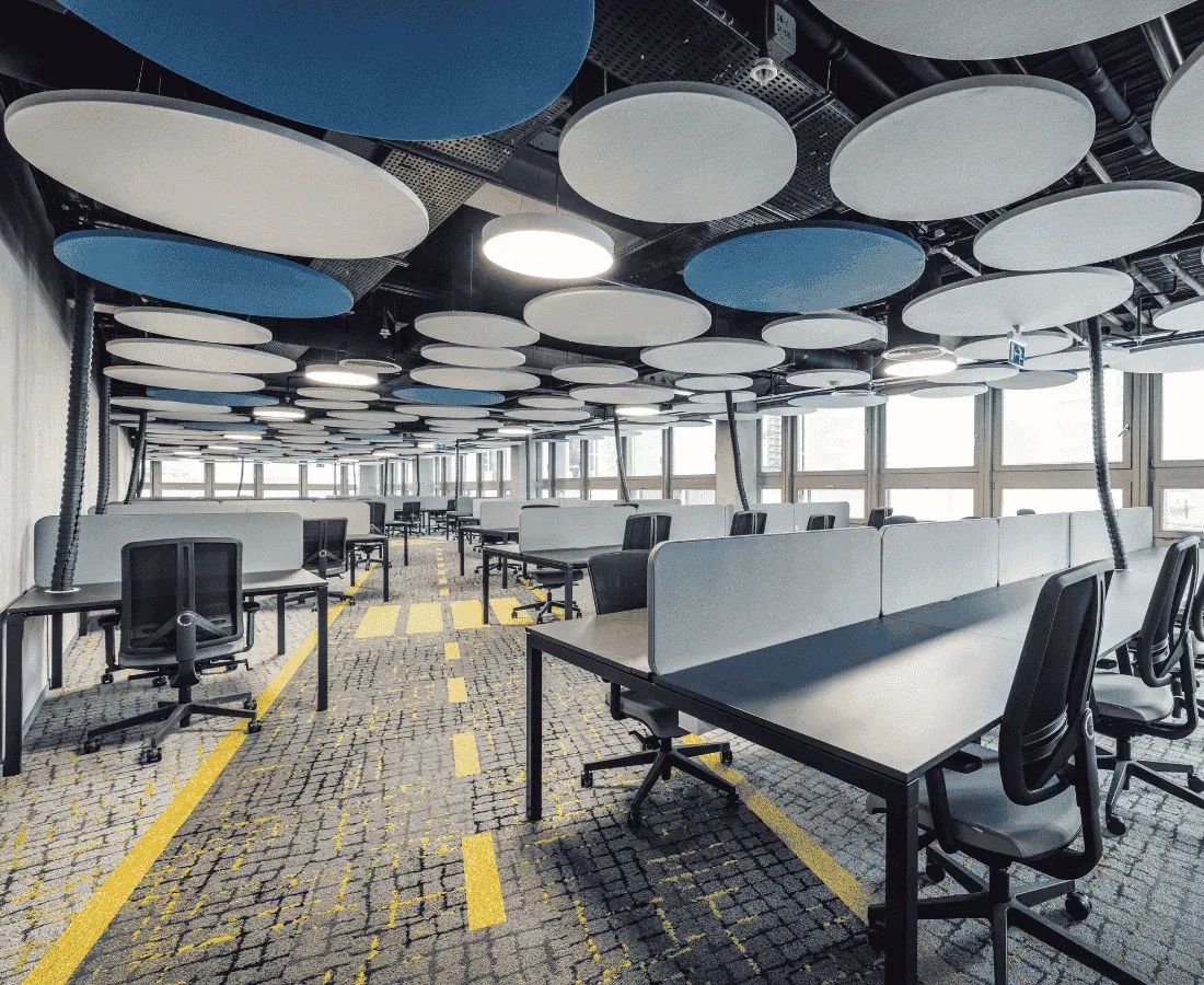An office space with unoccupied desks with modern lighting and design.