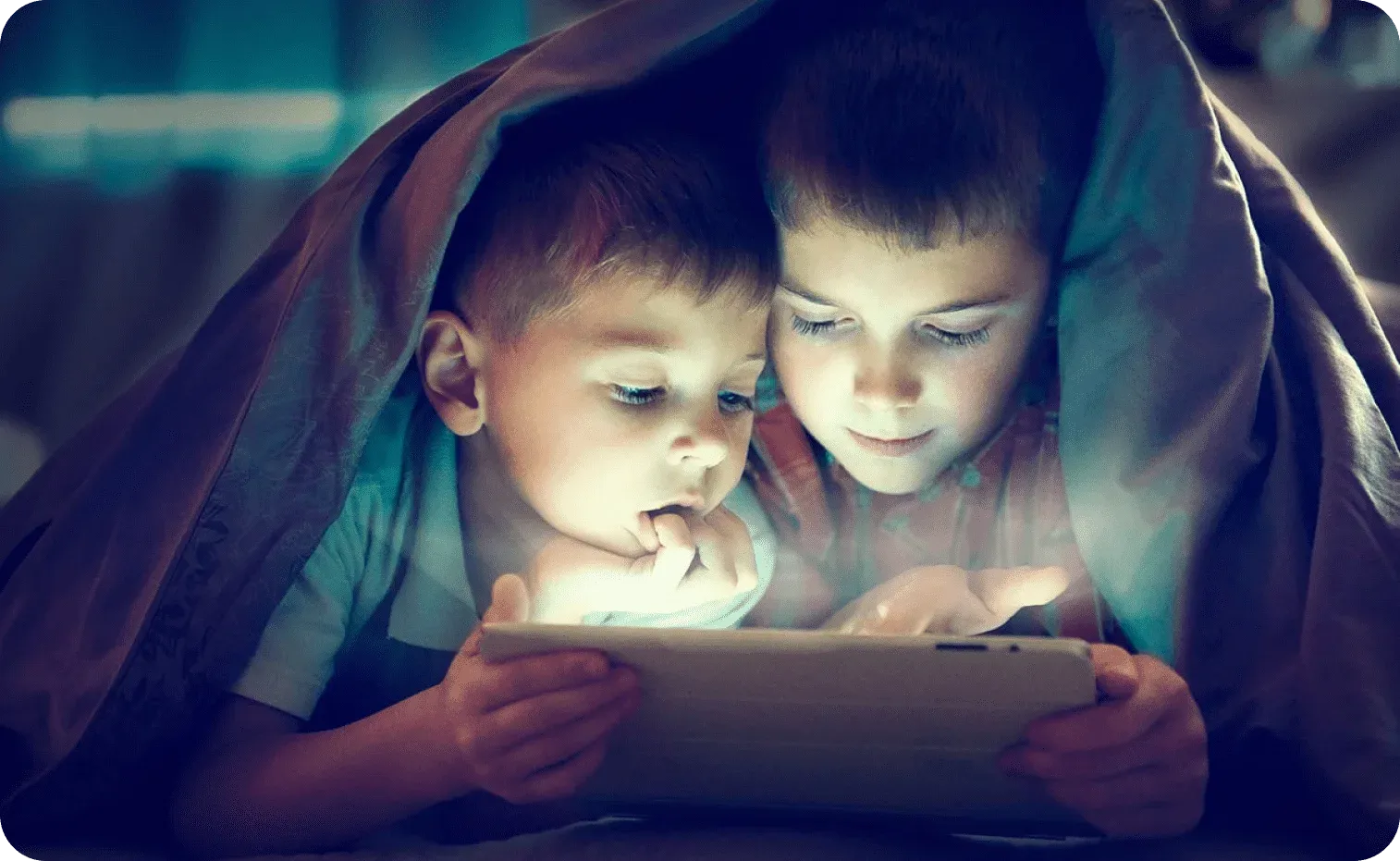 Little brothers playing on a tablet during bedtime