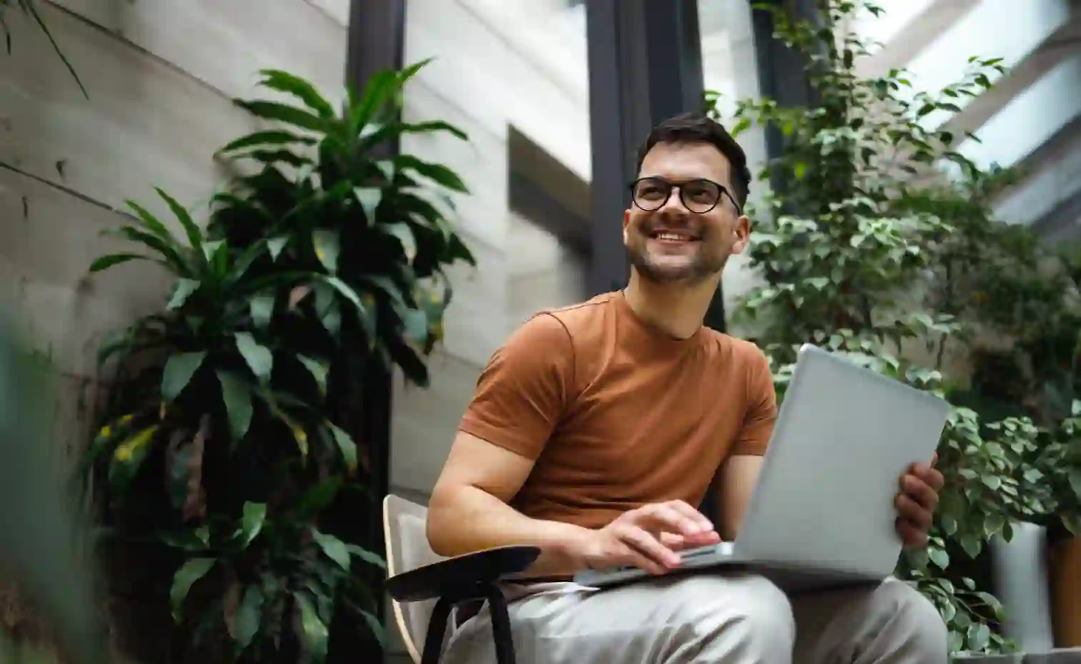 Young man sitting outdoors with his laptop in hands