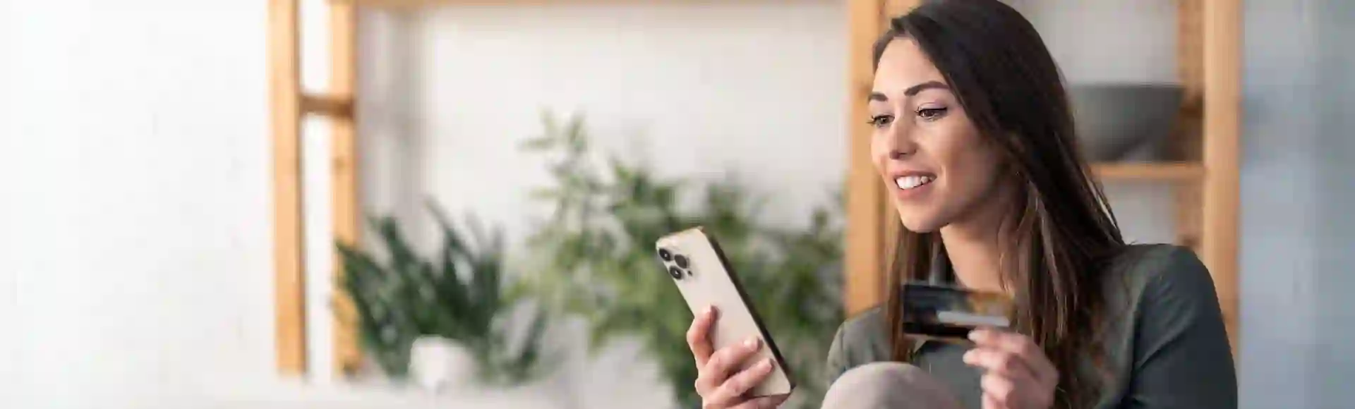 woman holding a credit card in one hand and a smartphone in the other, representing debt recovery solutions and AI-powered customer experience for businesses.