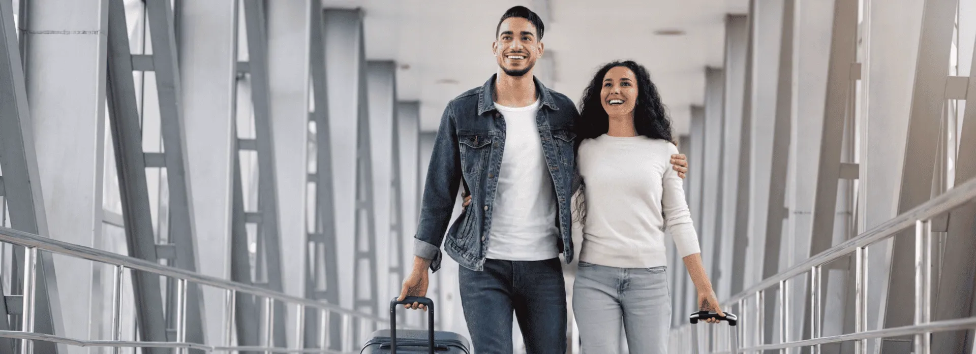 Smiling couple walking with luggage at an airport, symbolizing safe and stress-free travel.
