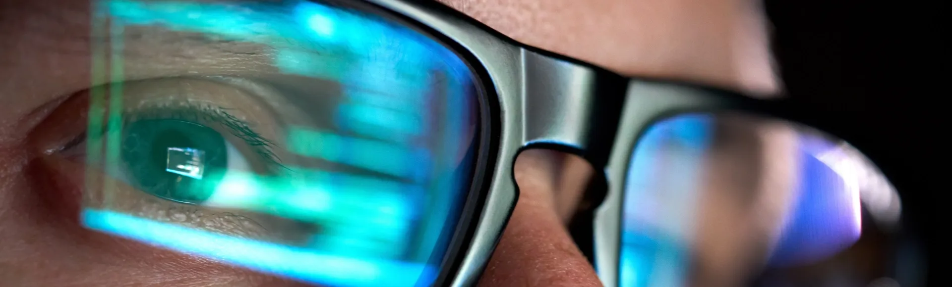 Close up of an eye with code reflected in glasses.