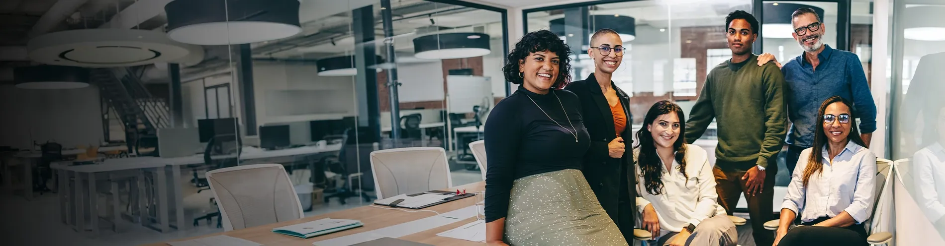 Diverse team smiling together in a modern office meeting room.
