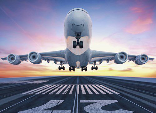 a large airplane takes off from a runway, with landing gear retraction against a backdrop of a colorful sunset sky, highlighting the motion and dynamic energy of flight.