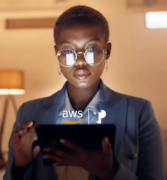 Young African woman wearing glasses uses an iPad in a warmly lit room.