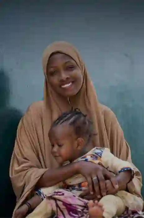 Woman holding a baby and smiling at the camera