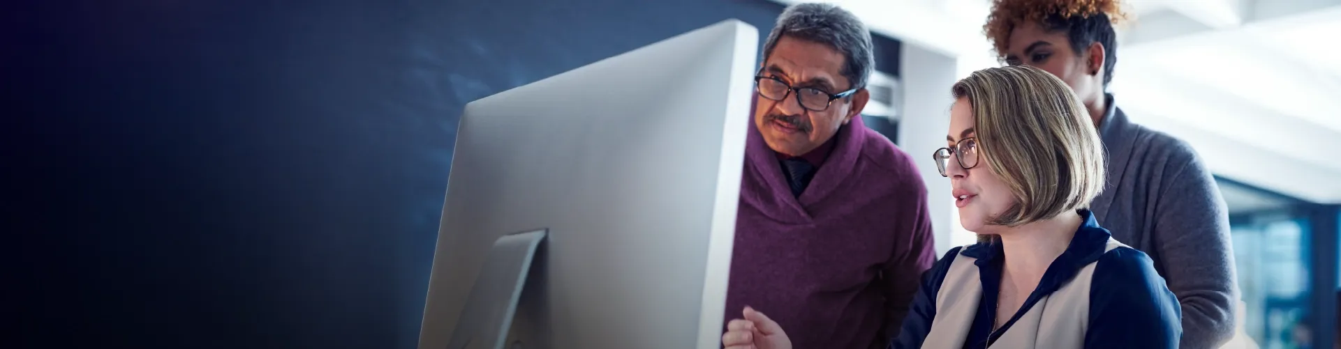 Team reviewing information together on a desktop computer in an office setting.