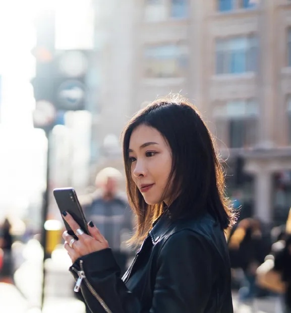 Professional woman using smartphone in a busy city street.