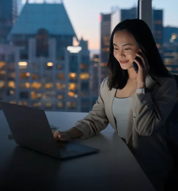 Asian business woman working on her laptop while talk in the phone in a modern office space
